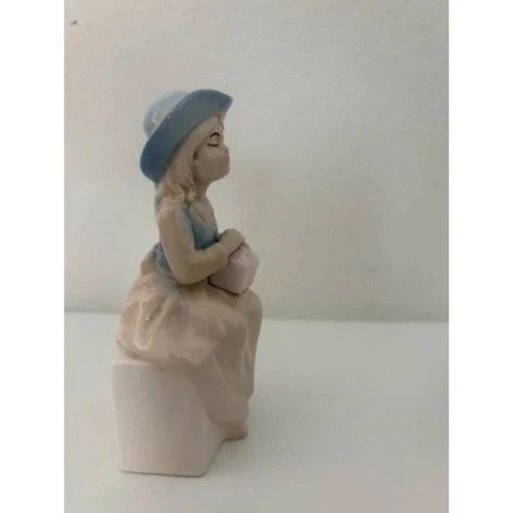 vtg. porcelain figurine of a seated girl wearing a blue hat